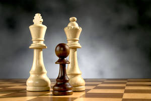 三個木製國際象棋棋子放在棋盤上，背景為煙灰色。