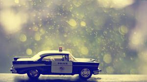 復古警車玩具在濕漉漉的路面上，金色散景雨滴背景。