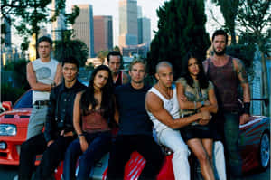 Fast and Furious 演員在日落時分的城市中，在一輛紅色汽車上擺姿勢。