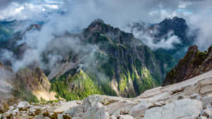 崎嶇的山脈，綠色的森林和雲朵在岩石地形上飄動。