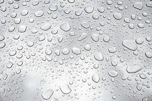 玻璃表面上的雨滴特寫，背景為柔和灰色。 — 雨 壁紙