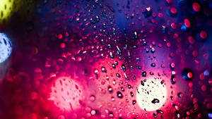 玻璃上的雨滴，背景有發光的霓虹燈