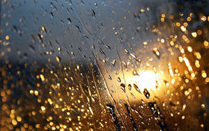 窗戶上的雨滴，背景是金色陽光的散景。