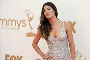 身穿銀色亮片連衣裙的女性在Emmys紅地毯活動中擺姿勢。