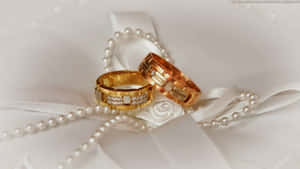 兩枚鑲有鑽石的金色結婚戒指在白色緞帶和珍珠上。