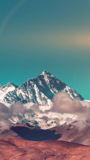 雪山山峰聳立於雲層和紅色沙漠之上，藍綠色天空