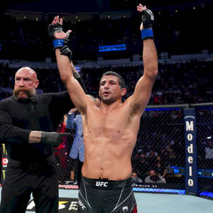 UFC拳手在八角籠內高舉雙臂慶祝勝利。