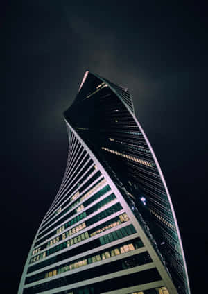 一座現代化的螺旋形摩天大樓在夜間被照亮，映襯著黑暗的天空。