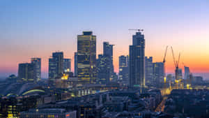 黃昏時分的城市天際線，發光的建築物和建築起重機 — 城堡 壁紙