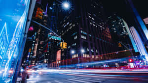 夜晚的城市街道，有移動車輛的光跡和燈火通明的摩天大樓。