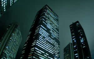 夜晚的城市景觀，高聳的摩天大樓在黑暗的天空下閃爍著發光的窗戶。