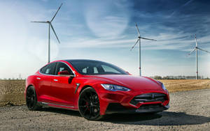 日落時分，紅色Tesla Model S Performance停泊在風力發電機附近。 — Tesla GIF 壁紙