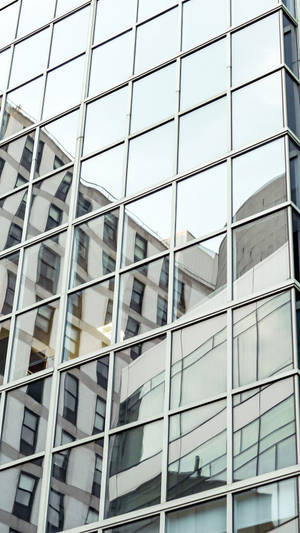 玻璃建築的特寫，反射其他城市結構和天空。 — Vivo Y11 壁紙