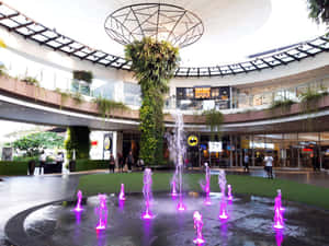 室內商場中庭，配有紫色燈光噴泉和垂直花園。 — 4:3 壁紙