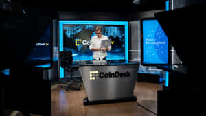 CoinDesk加密貨幣新聞主播在配備藍色數位顯示屏的高科技工作室中。