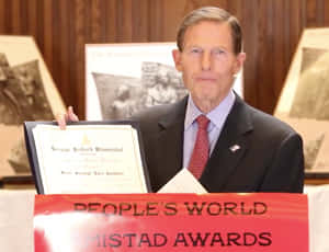參議員理查德·布盧門撒爾在People's World Mistad Awards活動中手持獎狀。