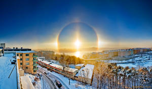 冬日城市景觀在日出時分，帶有明亮的太陽光暈和積雪的建築物。