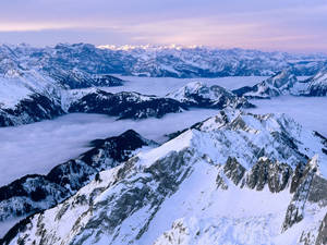 黎明時分，積雪的山脈聳立在雲海之上。 — 天空景觀 壁紙