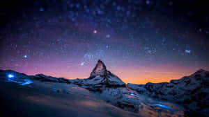 白雪覆蓋嘅山峰喺繁星點點嘅暮色天空下，下面有閃爍嘅光。
