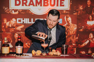 調酒師在帶有 Drambuie 品牌的酒吧中倒入粉紅色雞尾酒。