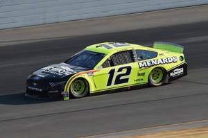 一輛檸檬綠和黑色的NASCAR賽車在賽道上飛馳。