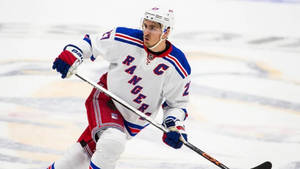 穿著 Rangers 隊服的冰球運動員在比賽中於冰上滑行。 — 康納·麥格雷戈 壁紙
