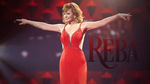 Reba McEntire 穿著紅色連衣裙在明亮的舞台上唱歌。