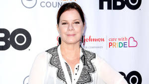 在HBO Pride活動中穿著白色蕾絲襯衫的女性對著鏡頭微笑