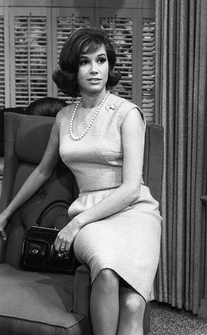 1960年代連衣裙和珍珠的女士手持手袋坐著