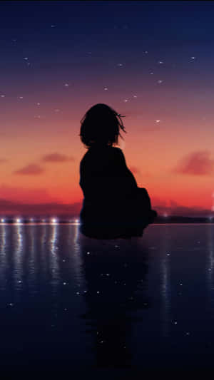 黃昏時分，星空下坐在水邊的人的剪影。
