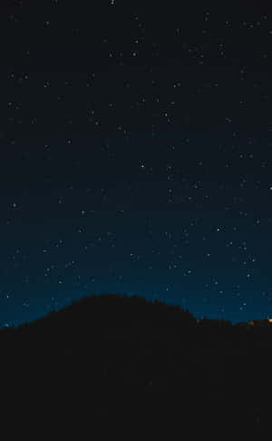 黑暗森林山丘上方的星空夜空與遠方燈光。