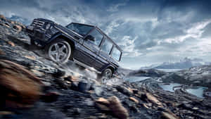 黑色 Mercedes G-Class SUV 在冰川湖附近的岩石山地地形上攀爬。
