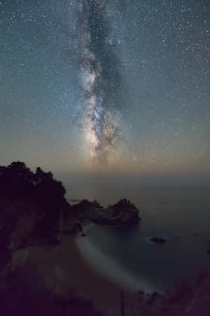 夜間霧氣瀰漫的海灣上空的銀河系
