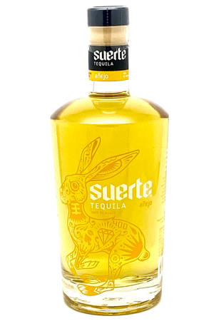 Suerte Añejo龍舌蘭酒瓶，帶有兔子設計和金色液體。