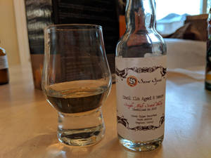 一瓶威士忌和一個品酒杯在木桌上。