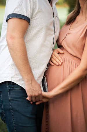 一個男人和一個孕婦在戶外溫馨的時刻手牽手。