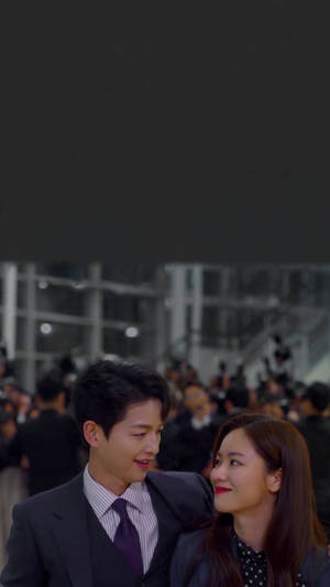 一名穿著正裝的男士和女士在擁擠的夜間環境中互相微笑。 — 意大利 壁紙