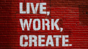 紅磚牆上以白色油漆寫著 live work create。