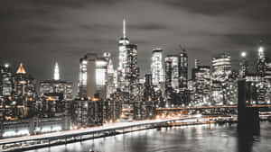 紐約天際線的夜景，有燈火通明的建築物和水上的橋樑。