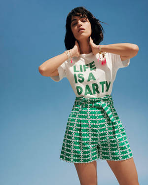 身穿綠色圖案短褲和印有「LIFE IS A PARTY」字樣白色T恤的女性。