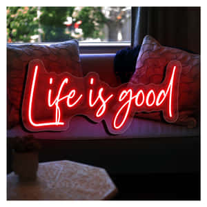 紅色霓虹燈牌寫著「Life is good」，在窗邊的梳化上。