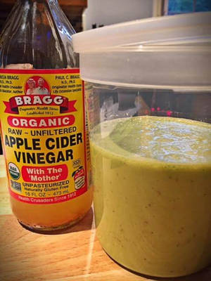 Bragg蘋果醋瓶旁邊有綠色沙律醬罐，在木枱上。