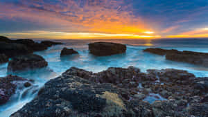 海洋上的夕陽，海浪拍打黑色岩石