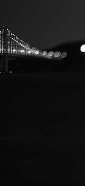 一座燈火通明的橋樑與發光燈光的模糊夜景。 — 沙灘 壁紙