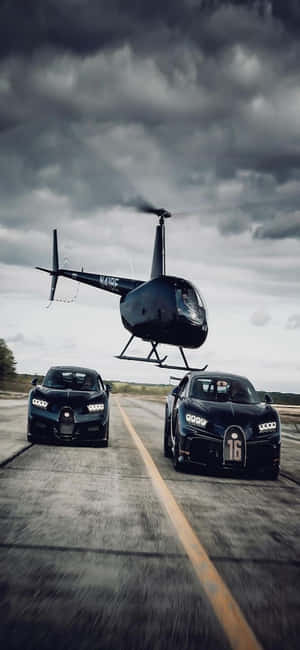 兩輛黑色Bugatti汽車在潮濕的道路上疾馳，一架直升機在上空盤旋。 — Xiaomi 15 壁紙