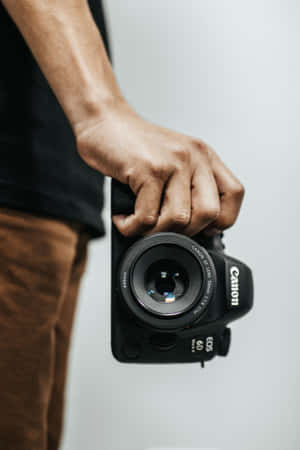 在攝影棚環境中手持黑色Canon DSLR相機。 — 小米Pad 9 Pro 壁紙