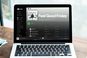 手提電腦在窗邊的木桌上顯示 Spotify 的「Feel Good Friday」播放清單。