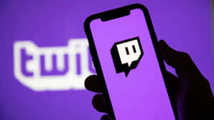 手拿著手機，顯示Twitch應用程式標誌，背景為紫色。
