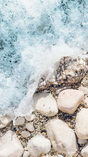 海浪拍打著陽光海灘上光滑的鵝卵石。