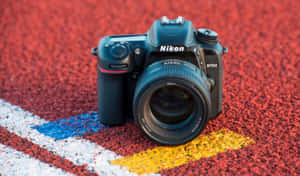 黑色 Nikon D7500 相機在紅色跑道上，帶有藍色和黃色標記。